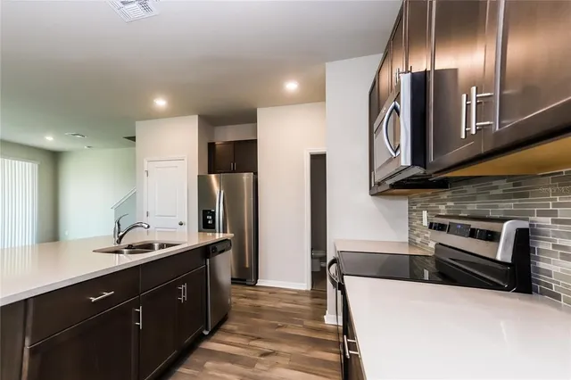 a kitchen with stainless steel appliances kitchen island granite countertop a refrigerator and a sink