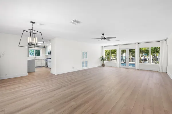 an empty room with wooden floor and ceiling fan