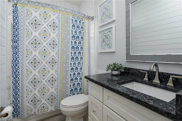 a bathroom with a granite countertop sink a toilet and a mirror