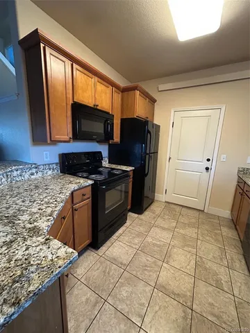 a kitchen with granite countertop a refrigerator and a stove top oven