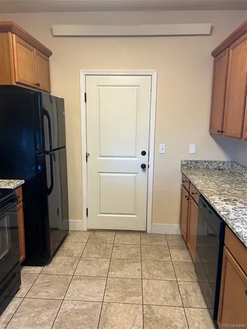 a view of a refrigerator in kitchen and an empty room in wooden floor