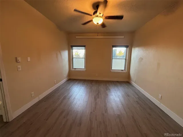 a view of empty room with wooden floor and fan