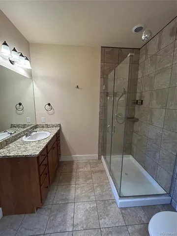a bathroom with a granite countertop sink a toilet and shower