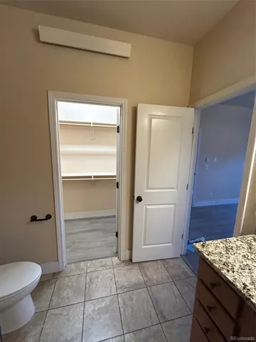 a bathroom with a granite countertop sink and a toilet