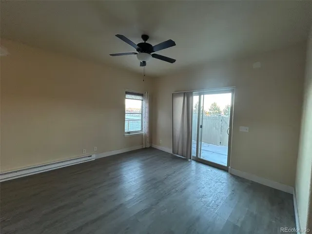 an empty room with wooden floor fan and windows