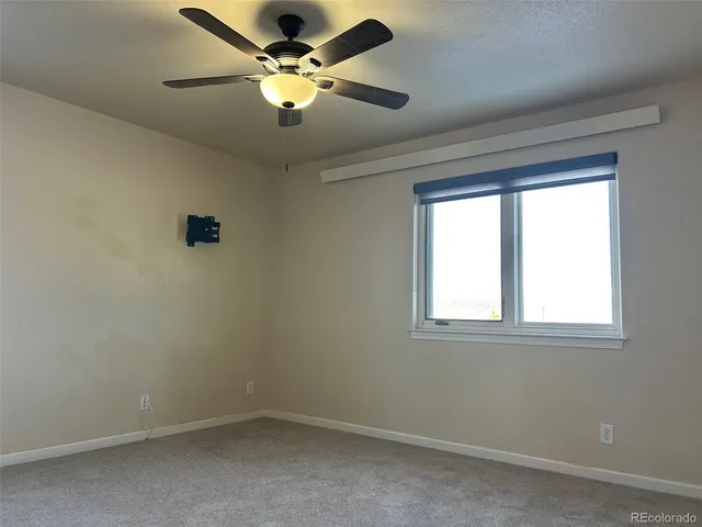 an empty room with a window and a fan