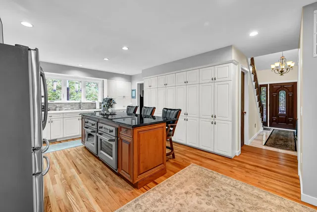 a kitchen with stainless steel appliances granite countertop a refrigerator a sink dishwasher a stove and a refrigerator with wooden floor