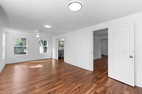 an empty room with wooden floor and windows
