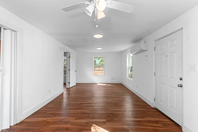 a view of an empty room with window and wooden floor