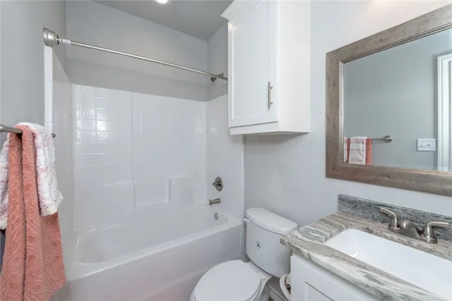 a bathroom with a granite countertop toilet a sink and a mirror