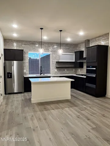 a large kitchen with kitchen island a large counter top stainless steel appliances and cabinets