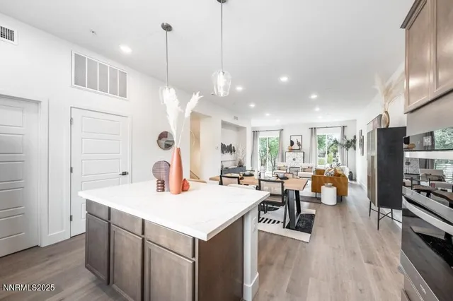 a open kitchen with stainless steel appliances granite countertop a sink dishwasher and a dining table with wooden floor