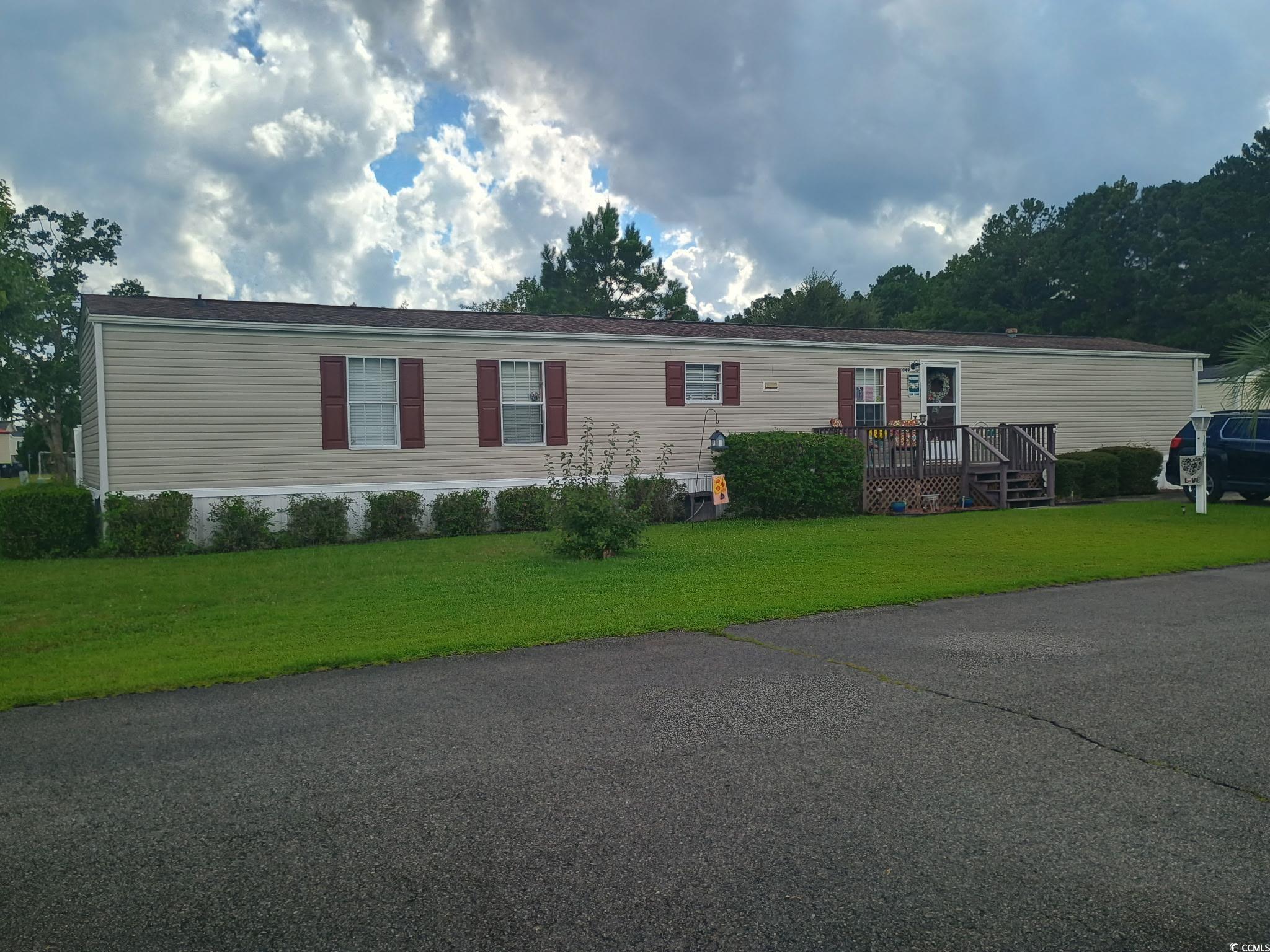 Manufactured / mobile home with a wooden deck and a front lawn