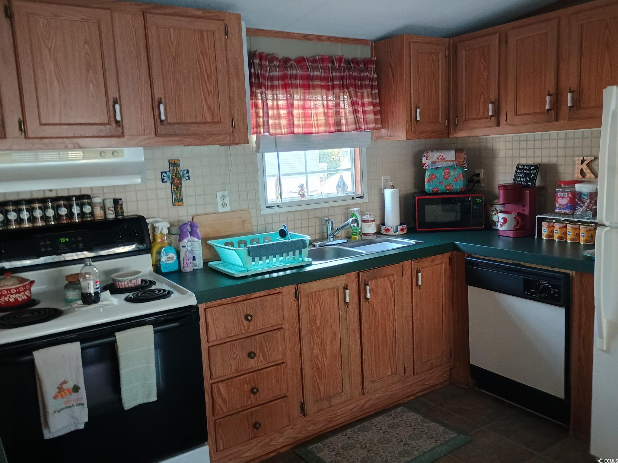 1049 Colonial Lane Conway, SC 29526 - Photo 9 of 27 Kitchen featuring white appliances, tasteful backsplash, range hood, and brown cabinets