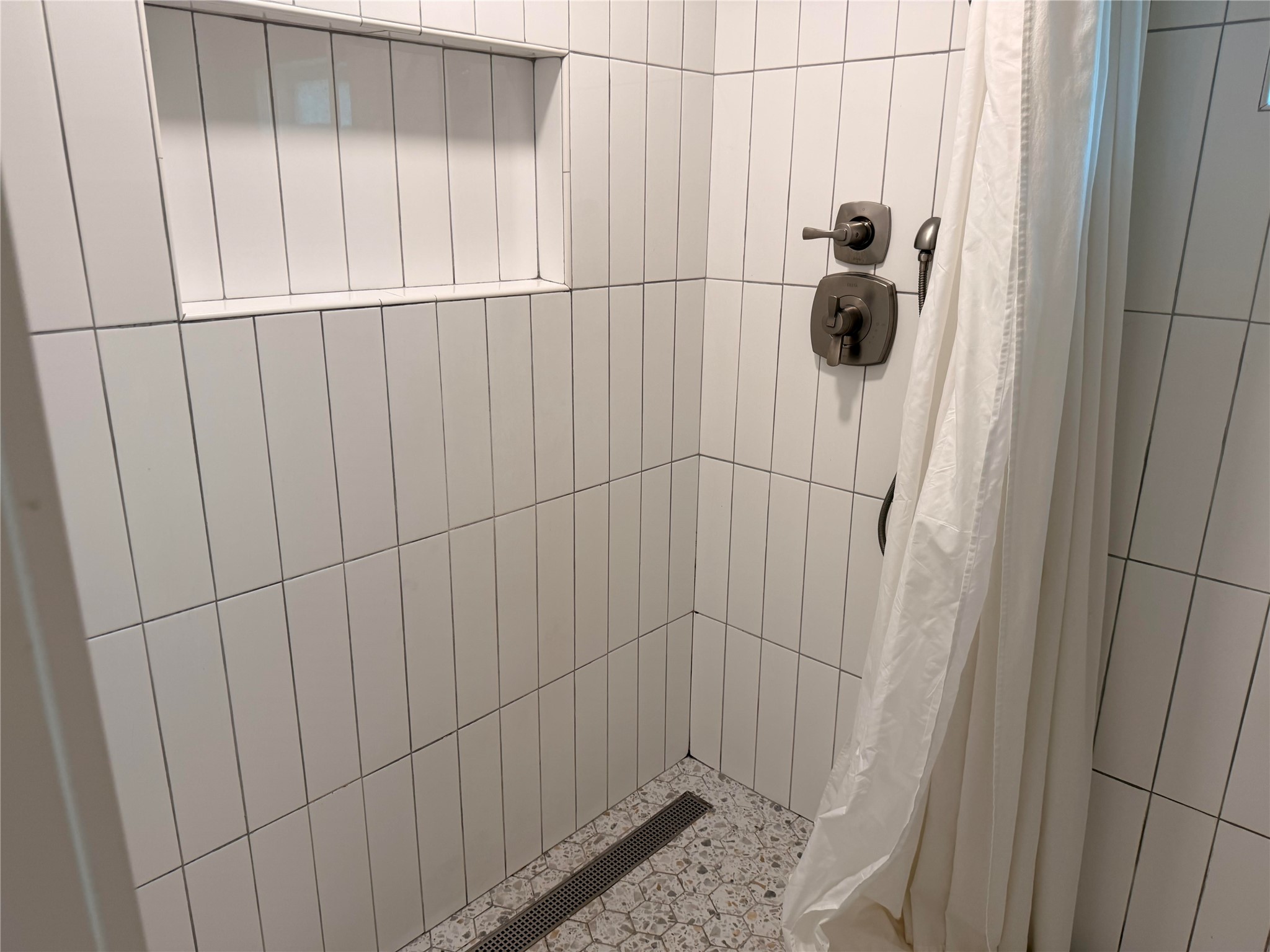 1182 Pandora Street Austin, TX 78702 - Photo 14 of 19 A well-appointed shower features sleek tile walls and practical built-in shelving.