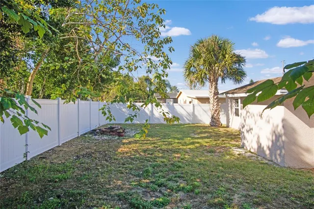a view of a white house with a big yard and large tree