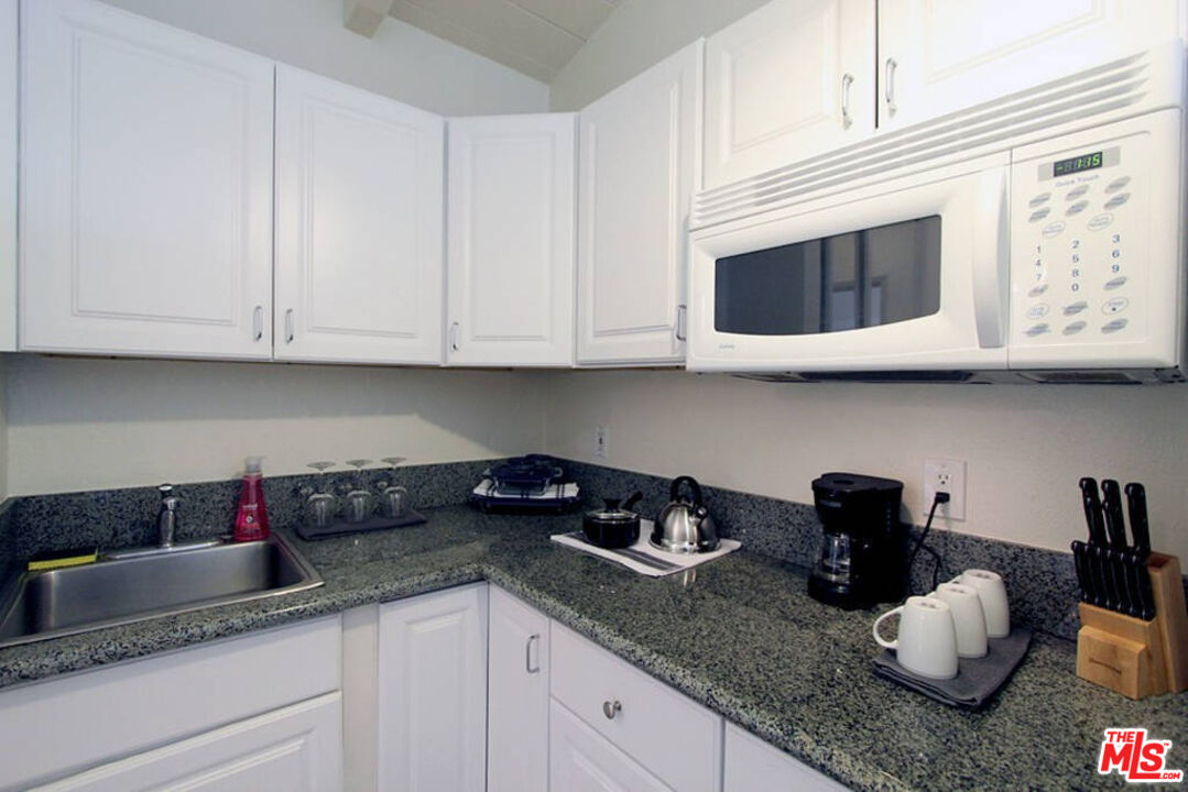 3005 Ocean Front Walk, Unit E Venice, CA 90291 - Photo 3 of 6 a kitchen with granite countertop white cabinets and sink
