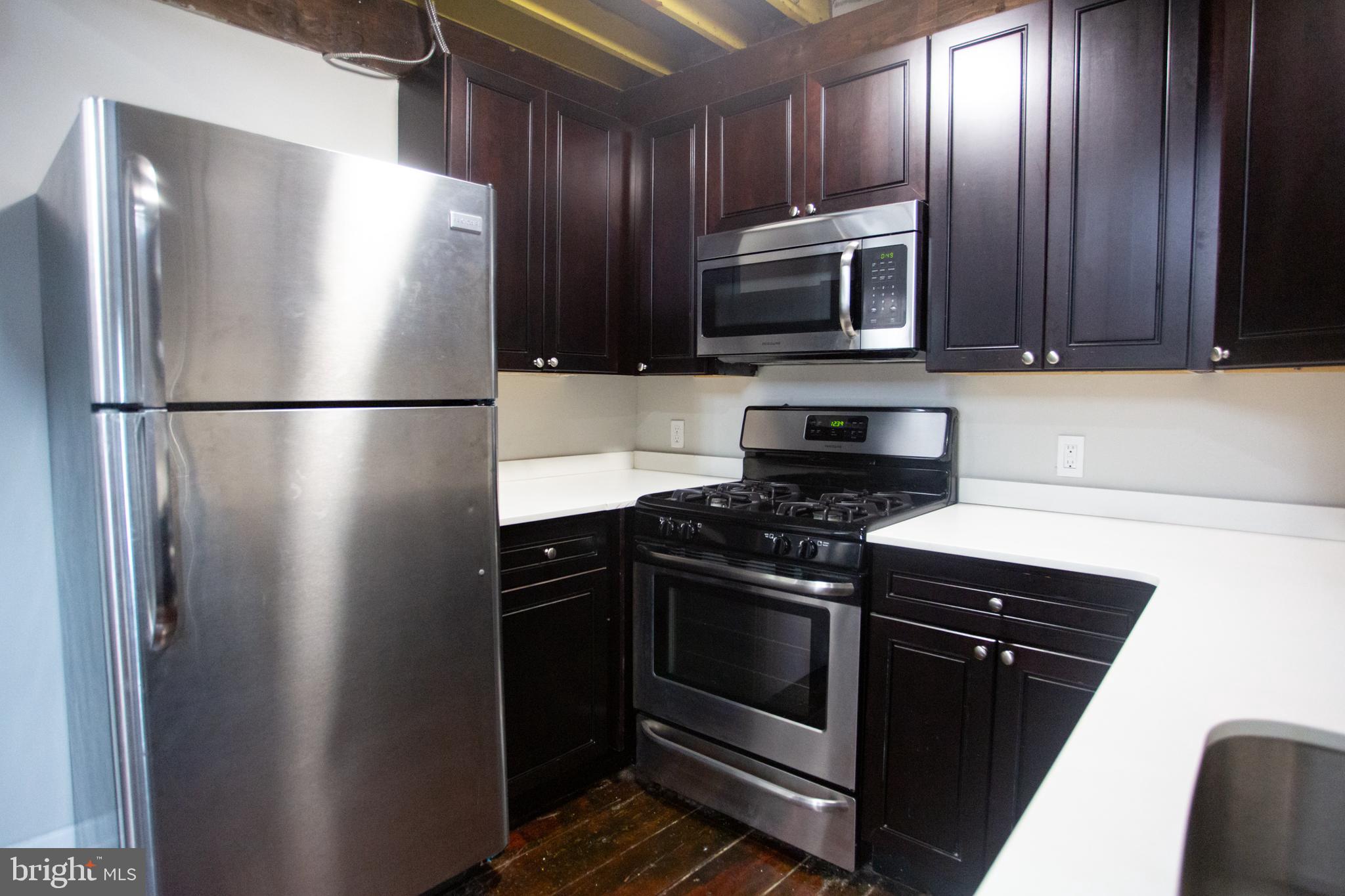 715 South 3rd Street, Unit 204 Philadelphia, PA 19147 - Photo 9 of 28 a kitchen with stainless steel appliances granite countertop a refrigerator stove and microwave