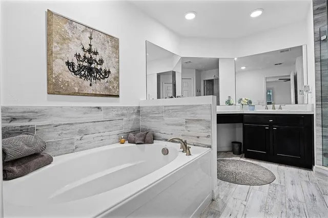 a bathroom with a tub a sink and mirror