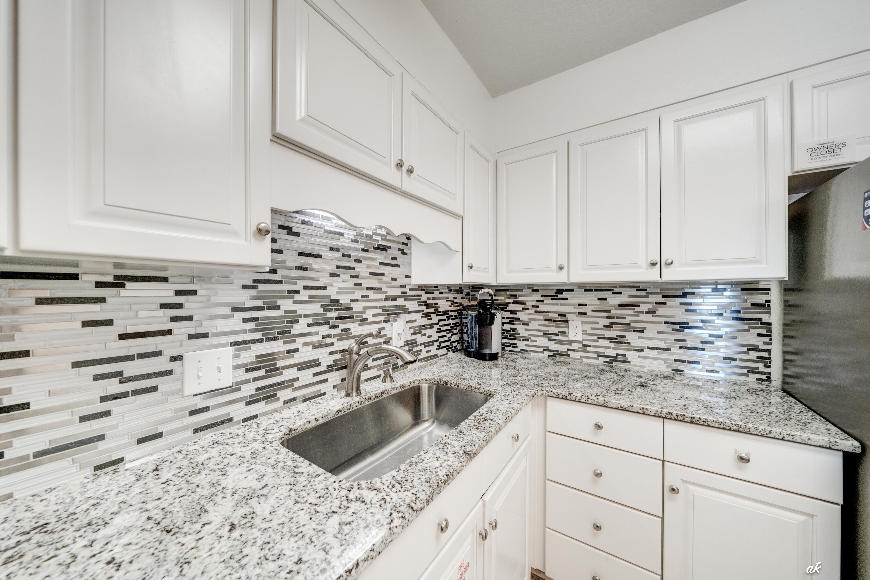 30 Moreno Point Road, Unit 404A Destin, FL 32541 - Photo 6 of 52 a kitchen with granite countertop white cabinets sink and stainless steel appliances