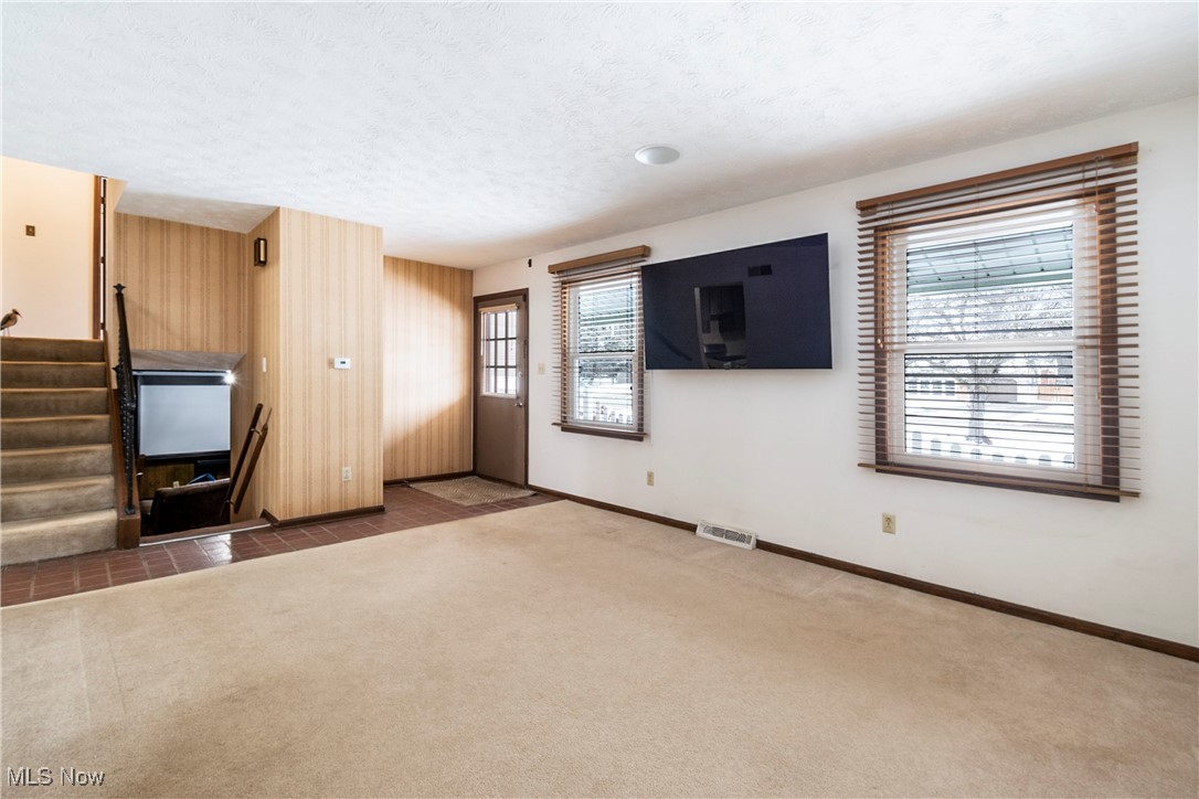 4875 New Road Youngstown, OH 44515 - Photo 25 of 25 Unfurnished living room featuring a textured ceiling, wooden walls, carpet floors, and plenty of natural light