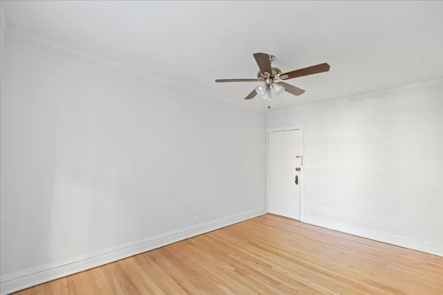 a view of a room with wooden floor and a ceiling fan