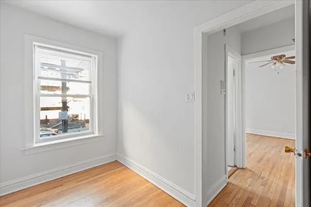 a view of an empty room with window and wooden floor