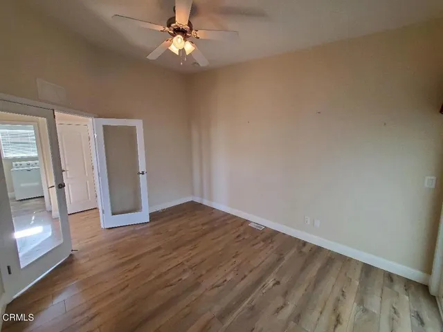 a view of an empty room with window and wooden floor