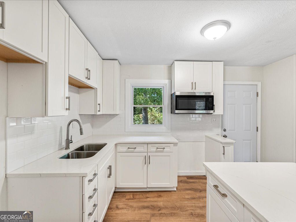 2905 Gresham Rd S East Atlanta, GA 30316 - Photo 11 of 27 a kitchen with granite countertop a sink stainless steel appliances and white cabinets