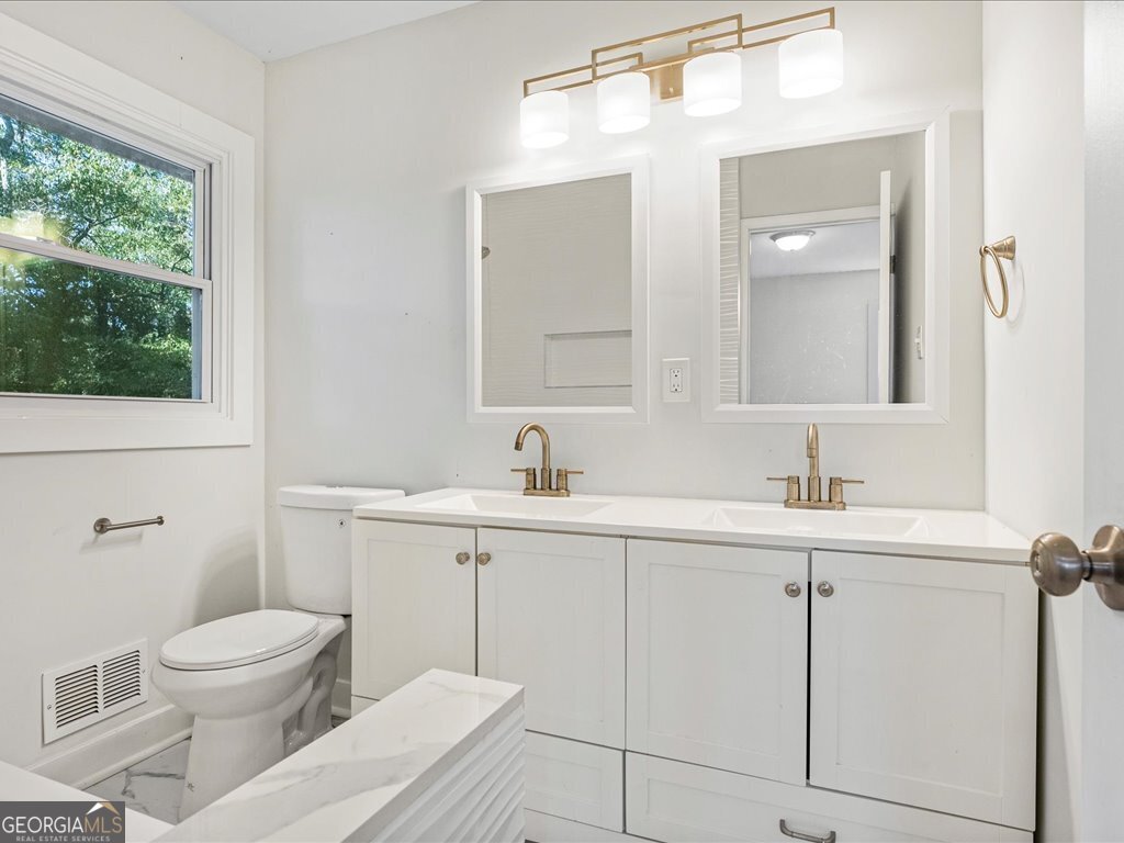 2905 Gresham Rd S East Atlanta, GA 30316 - Photo 21 of 27 a bathroom with a toilet a sink a mirror and a window