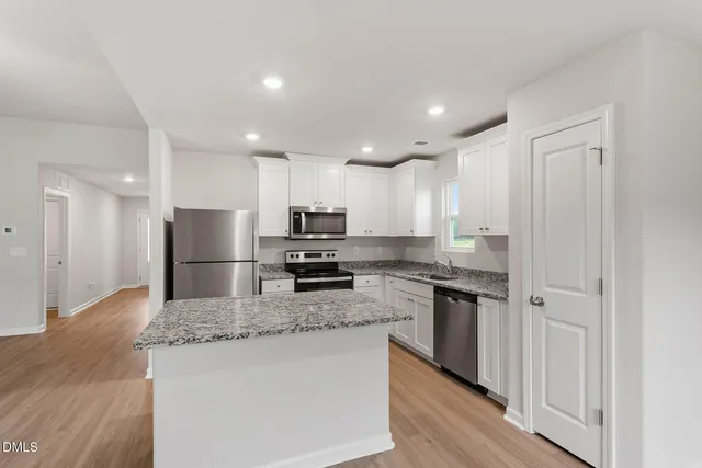 a kitchen with stainless steel appliances granite countertop a refrigerator a stove top oven a sink and dishwasher