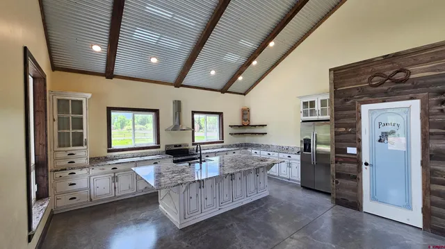 a large living room with stainless steel appliances kitchen island granite countertop furniture and a large window