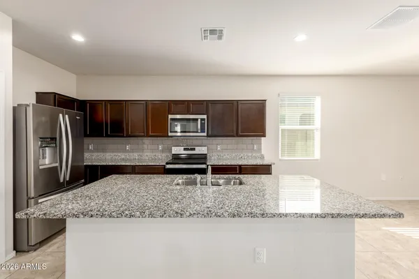 a kitchen with stainless steel appliances granite countertop a sink dishwasher stove and refrigerator