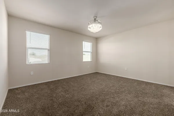 a view of an empty room and a chandelier fan