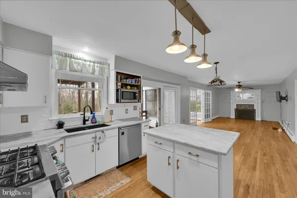 a kitchen with granite countertop a sink a stove cabinets and wooden floor