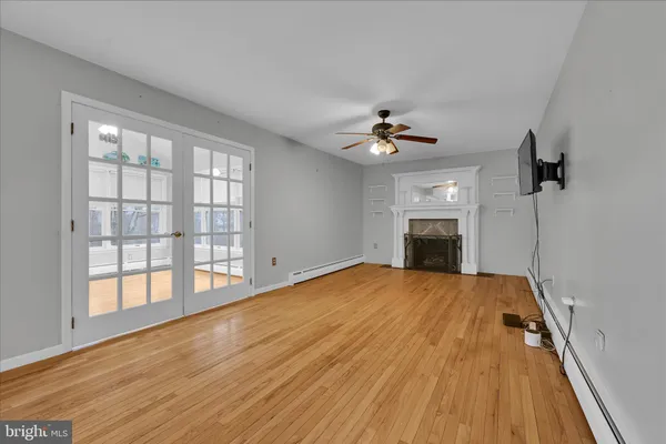 a view of empty room with wooden floor and fan