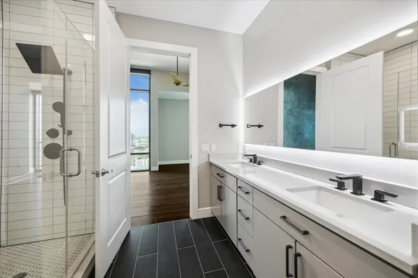 a spacious bathroom with a double vanity sink a mirror and shower