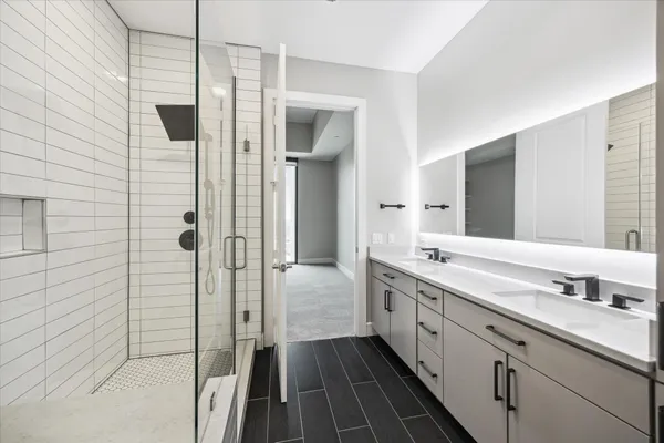 a spacious bathroom with a double vanity sink a mirror and a shower