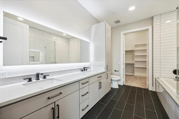 a spacious bathroom with a double vanity sink a mirror and a