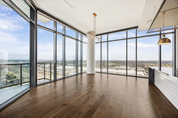 a view of an empty room with wooden floor and windows