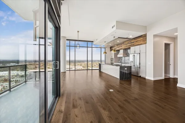 a view of a hallway with wooden floor and a kitchen