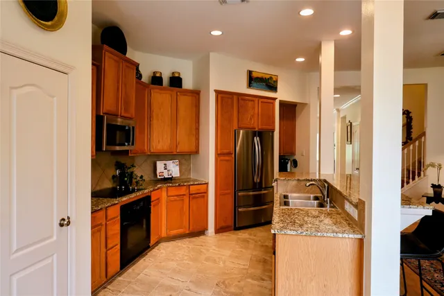 a kitchen with stainless steel appliances granite countertop a refrigerator and a sink