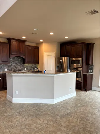 a kitchen with stainless steel appliances granite countertop a refrigerator a sink a stove a microwave and cabinets