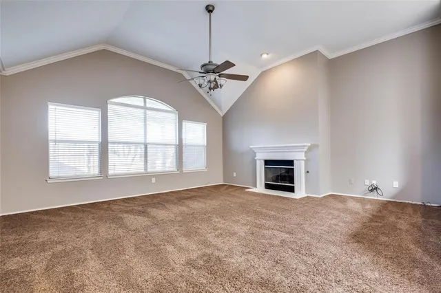 an empty room with chandelier fan and windows