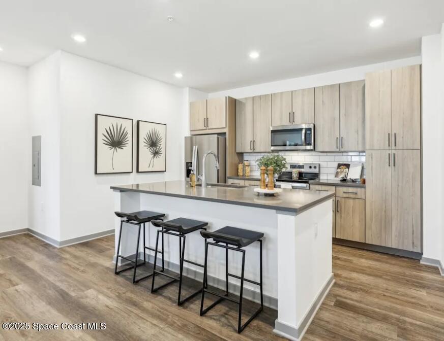 1073 Journey Circle, Unit 106 Rockledge, FL 32955 - Photo 7 of 10 a kitchen with stainless steel appliances granite countertop a stove a sink a refrigerator and white cabinets with wooden floor