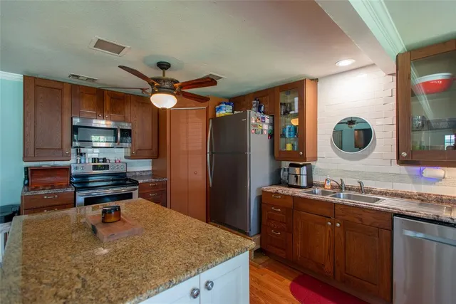 a kitchen with kitchen island granite countertop a sink a stove and refrigerator