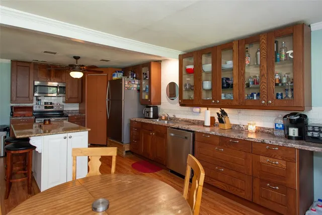 a large kitchen with kitchen island granite countertop a large window and stainless steel appliances