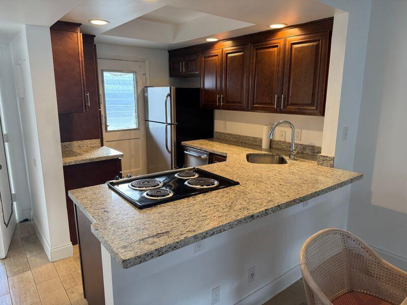 5401 Northwest 2nd Avenue, Unit 219 Boca Raton, FL 33487 - Photo 2 of 15 a kitchen with granite countertop kitchen island stainless steel appliances a sink stove and cabinets