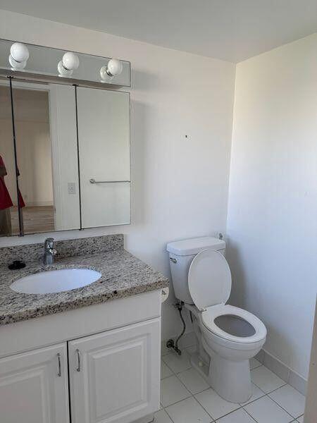 5401 Northwest 2nd Avenue, Unit 219 Boca Raton, FL 33487 - Photo 7 of 15 a bathroom with a granite countertop toilet a sink and a mirror