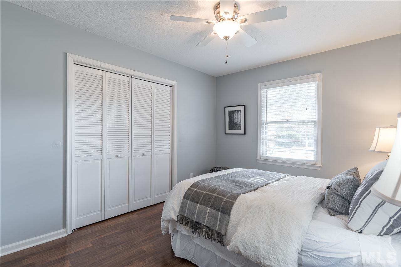 8608 Stonegate Drive Raleigh, NC 27615 - Photo 14 of 25 a bedroom with a large bed and a chandelier